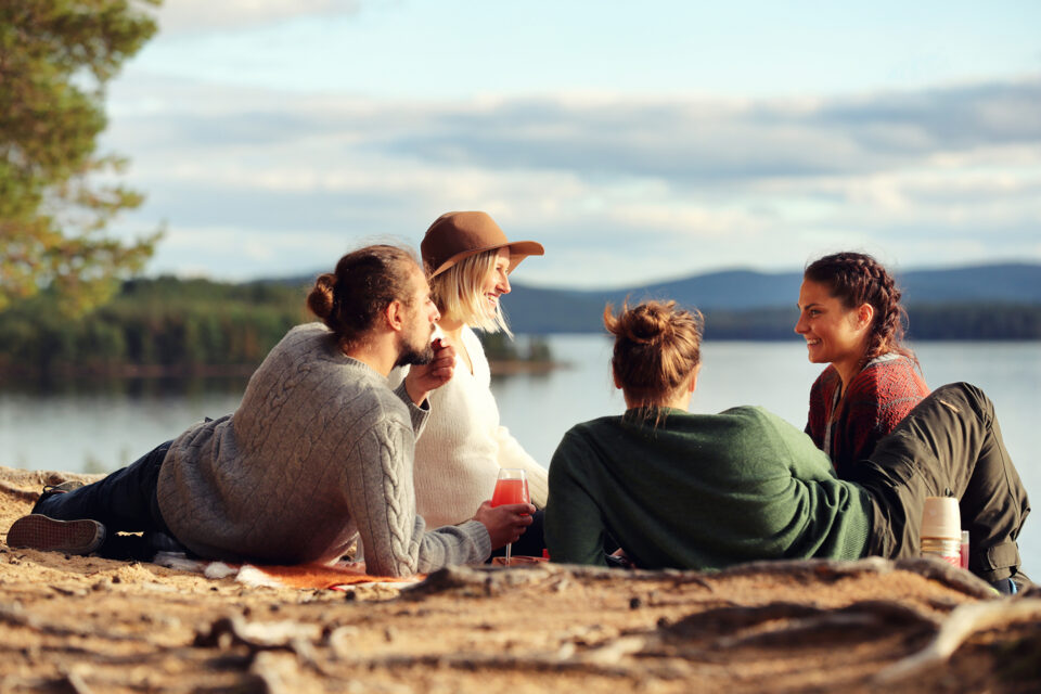 Pieni porukka istumassa aurinkoisella kalliolla järven rannalla.